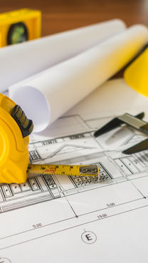 construction-plans-with-yellow-helmet-and-drawing-tools-on-bluep.jpg