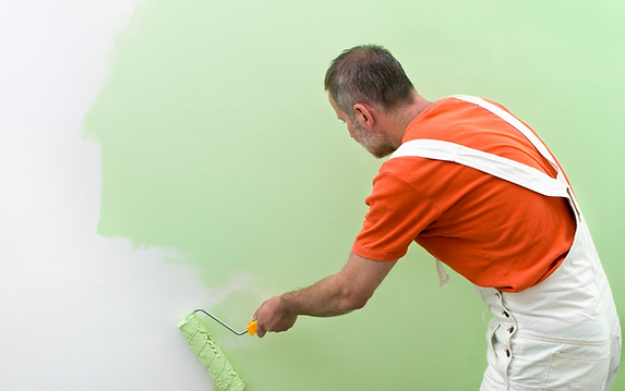 Maler malt Wand in grüner Farbe
