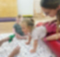 Child with disability and gross motor delay participating in paediatric physiotherapy over a therapy bolster with a trained paediatric physiotherapist
