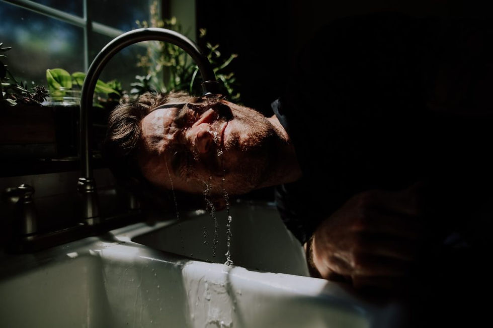 Man with a hangover holding his face under cold water