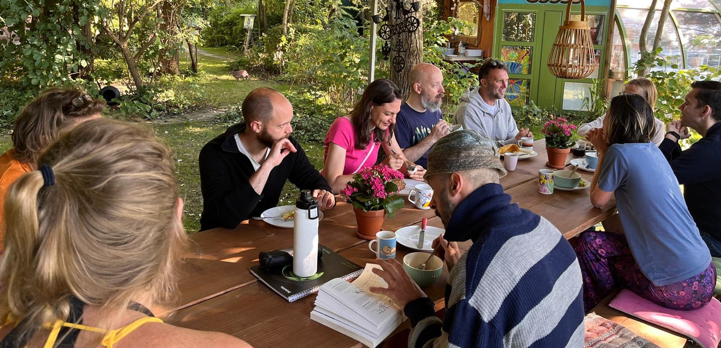 Group of people gathered around a table outdoors, enjoying a meal together