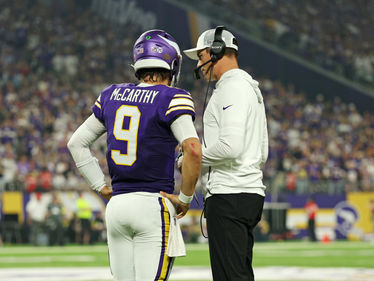 Vikings Head Coach Kevin O'Connell discusses strategy with Quarterback JJ McCarthy on the sidelines during a game, as the team prepares for the next play.