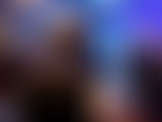 From behind, a Scottsdale wedding DJ with short gray hair commands the dance floor at a chic indoor wedding. Guests move to the music amid glowing uplights and refined event styling.