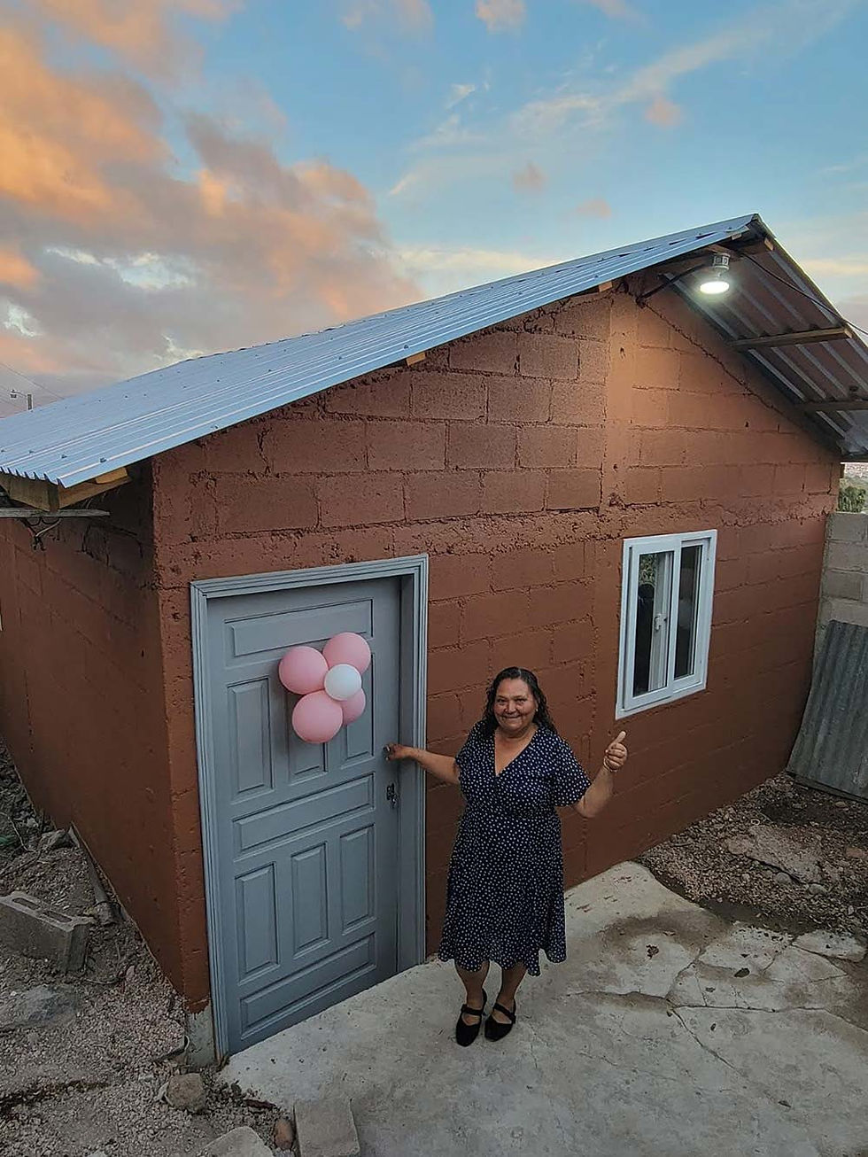 Woman smiling and giving a thumbs up in front of a new home with pink balloon decoration on the door