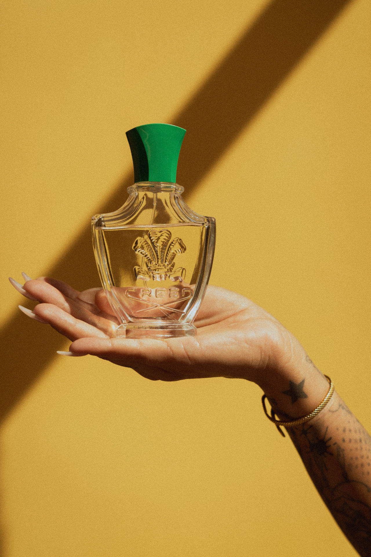 bride holding her perfume in her palm with the yellow wall background and shadow
