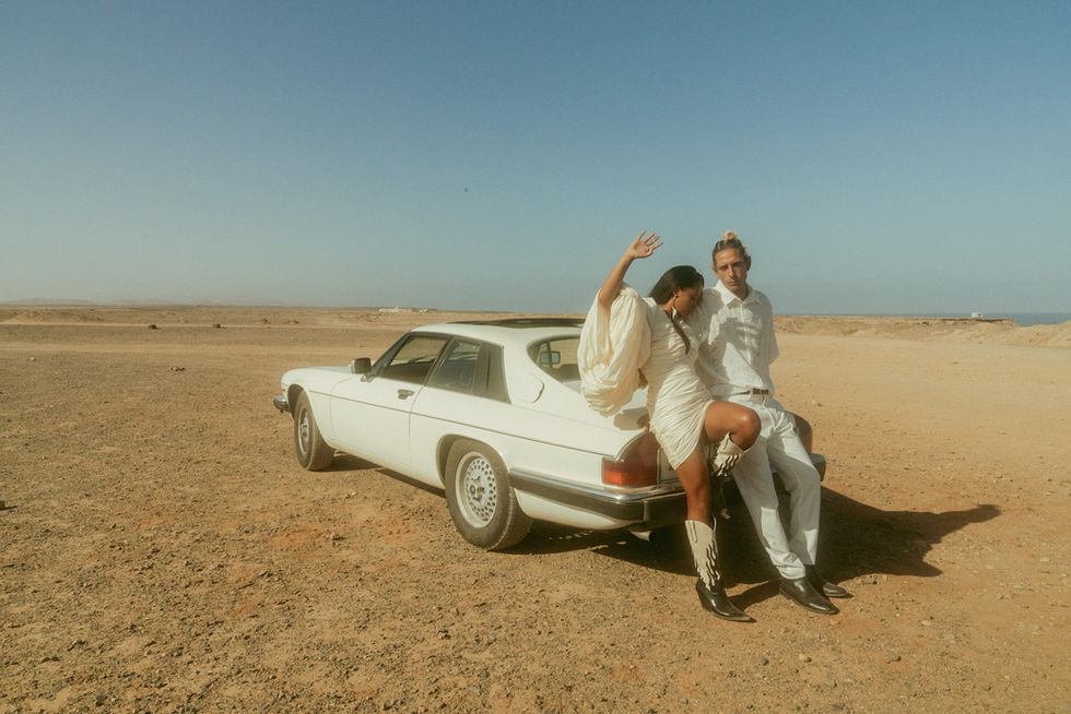 Couple posing beside a vintage car on a coastal cliff in Fuerteventura