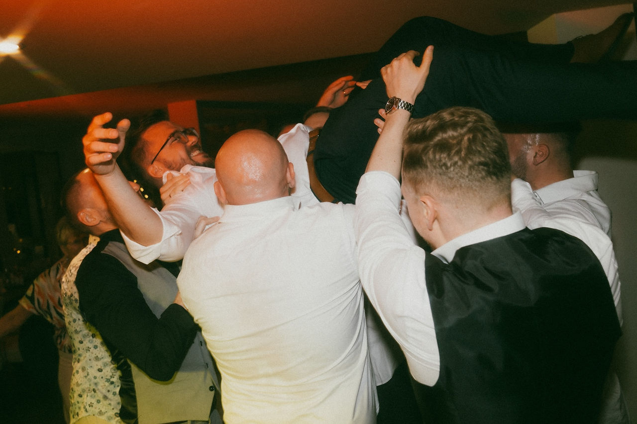 guests threw the groom in the air and the groom laughing and having fun