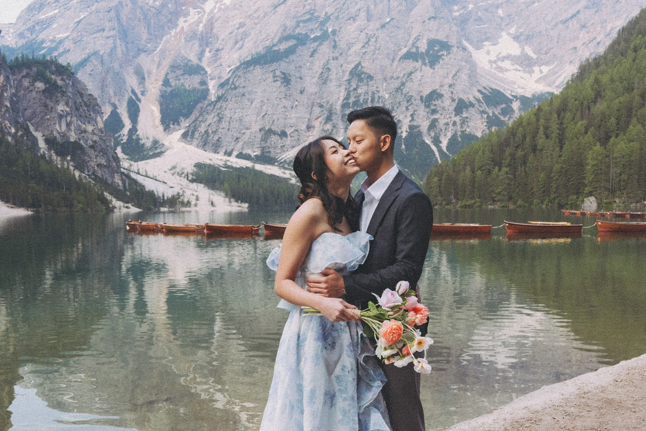 candid moment of the groom kissing the bride's face with the backdrop of the pragser wildsee and the alpine 