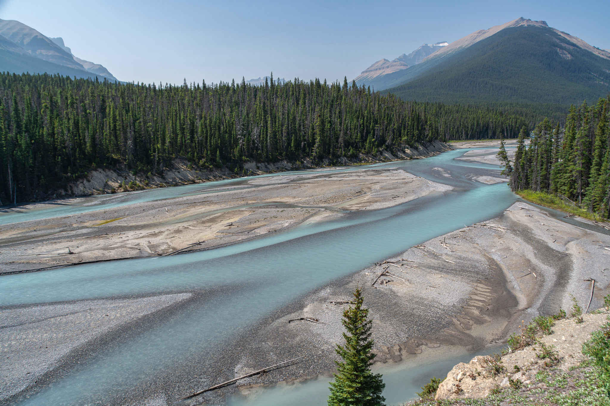 Turquoise river flowing through forest with mountains in the background. Smittys Smicko Phot