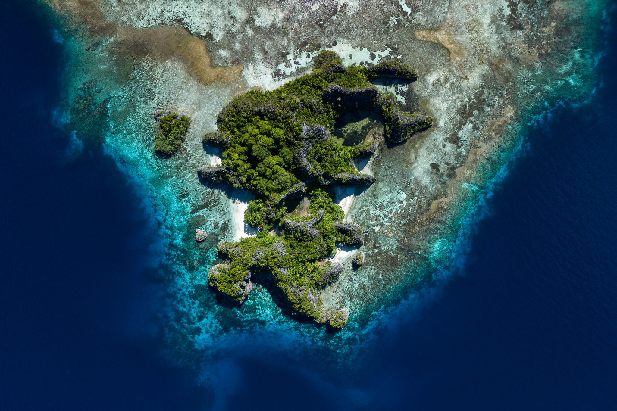 Aerial view of a small tropical island surrounded by turquoise waters.