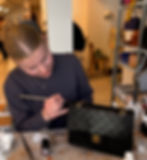 Vrouw restaureert een zwarte Chanel tas met een penseel