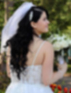 Belle mariée en robe blanche regarde au loin, bouquet de fleurs, nature en arrière-plan.