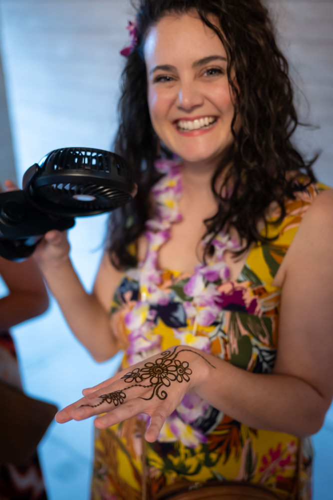 A woman shows off her henna design by Henna Hands Nida with a big smile.