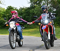A couple holding hands while riding their motorcycle.