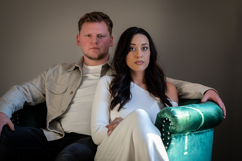 stoic faced couple posing on green arm chair