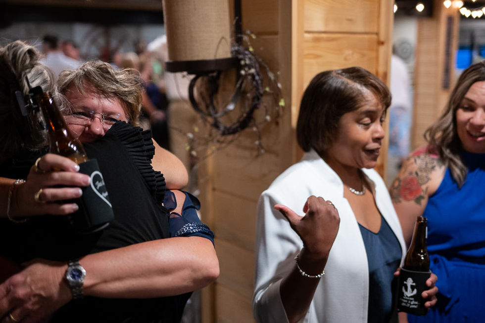 Jacqueline hugging a friend while Shonda makes a funny face telling a story to other guests.