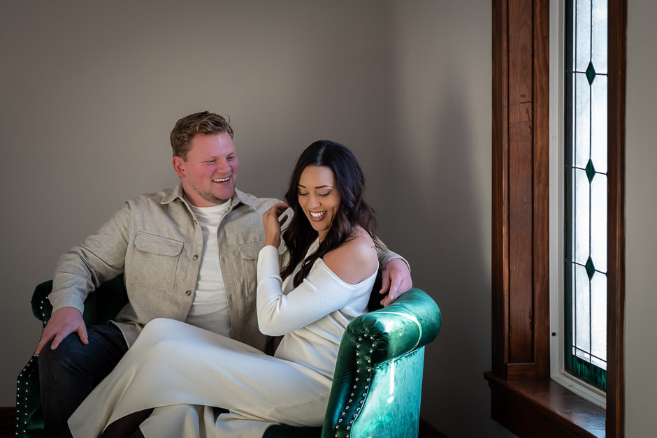 Couple sitting together on cute green chair at Warren Place Venue