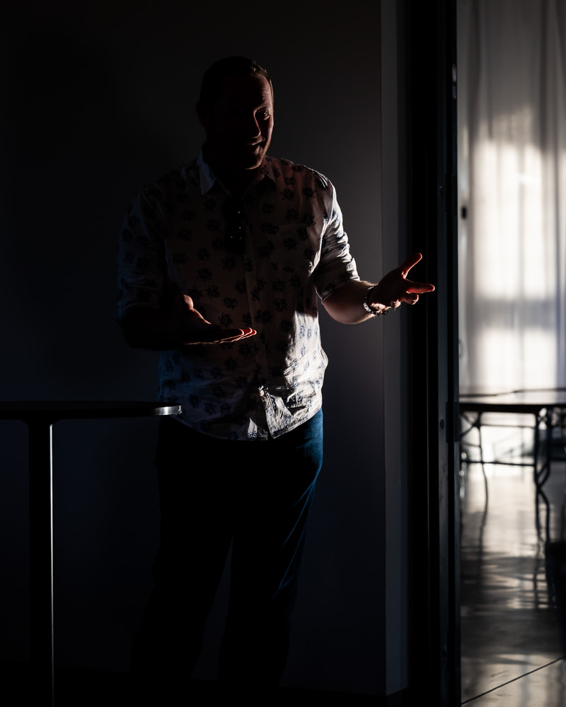 Male speaker using expressive hand gestures with bold lighting contrast