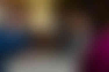 Groom laughing with friend with bride and father of the bride in the background