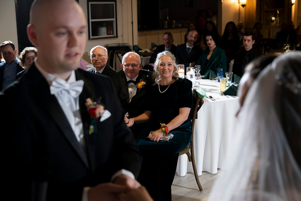 Bride’s parents emotionally reacting during the exchange of rings, couple blurred in the foreground