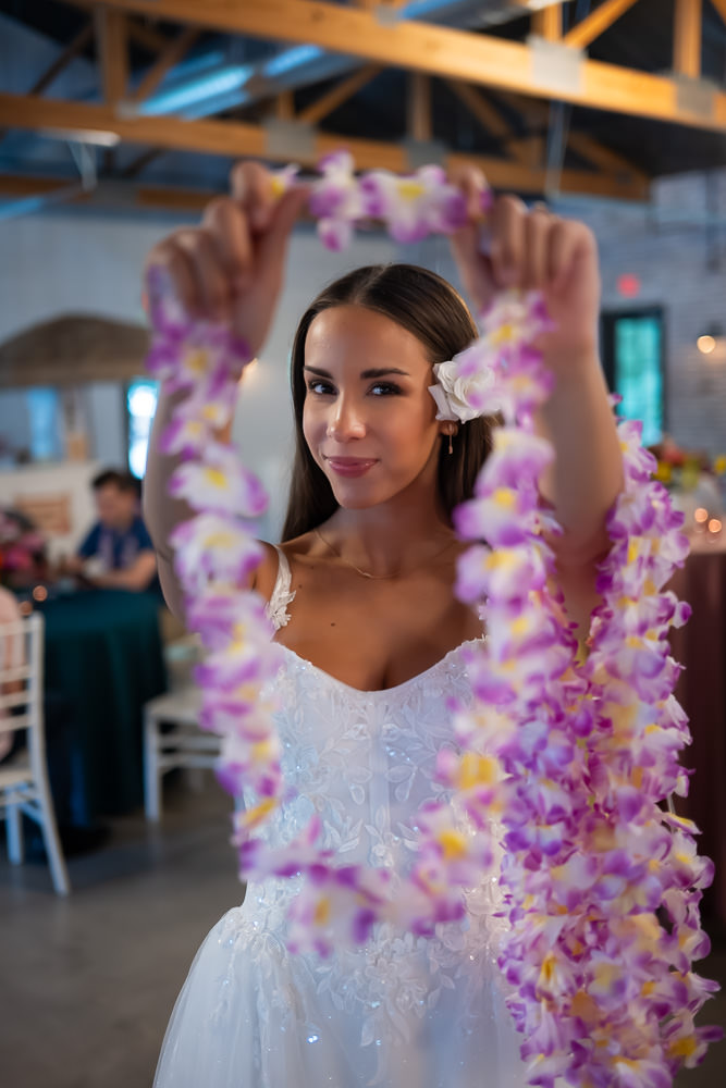 Colorful leis and a smiling bride welcome guests at the tropical-themed entrance of The Farmhouse KC.