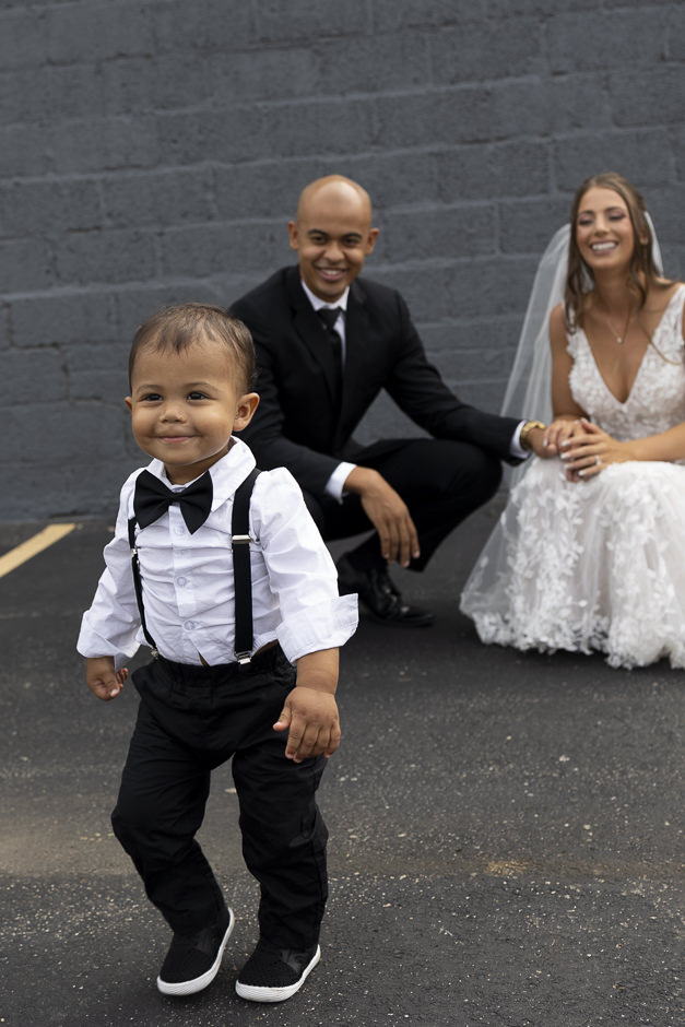 Son running from bride and groom and smiling at wedding