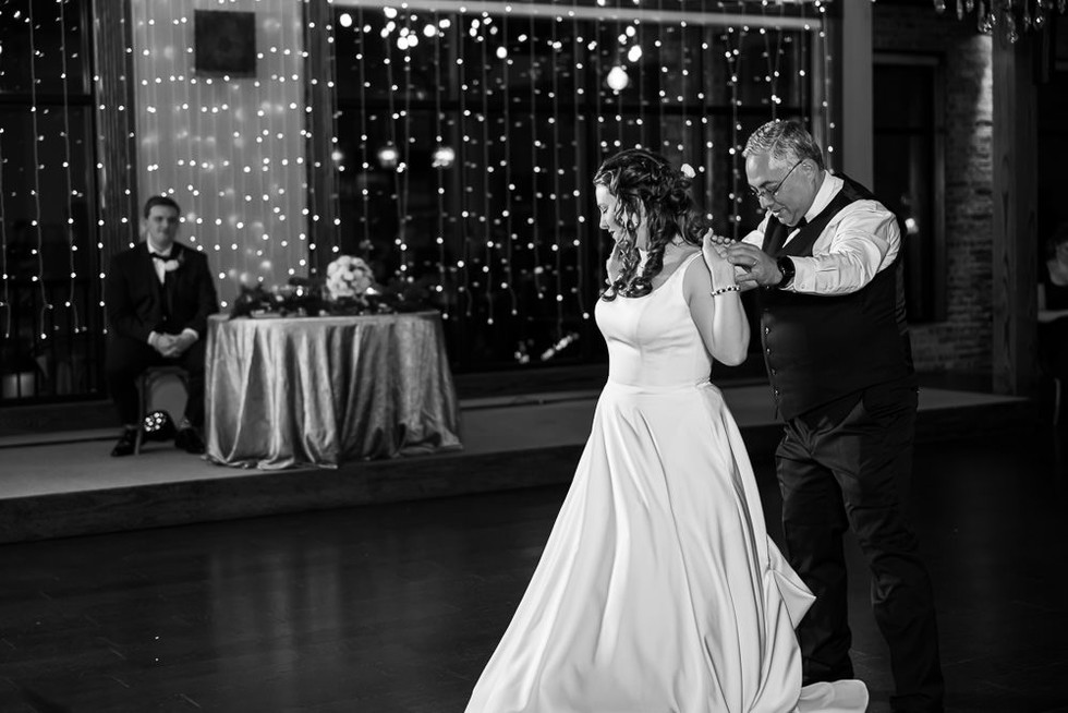 Black and white photo: The bride shares a special dance with her father, while groom Drake looks on in the background.