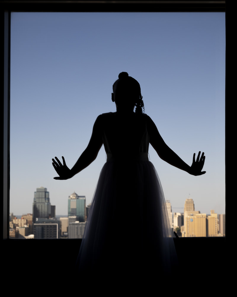 Flower girl in silhouette standing in front of the Kansas City skyline view.