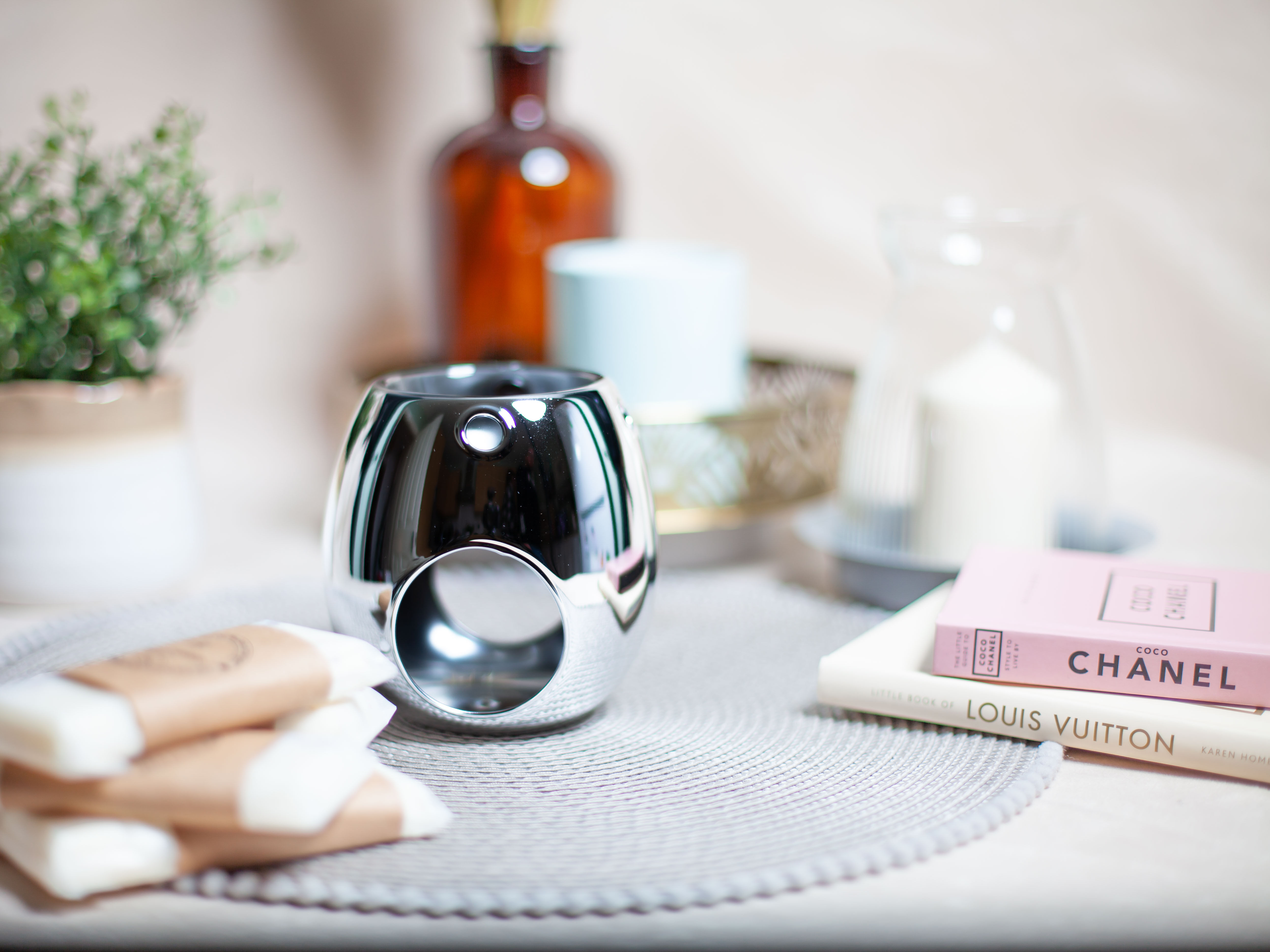 Silver wax melt warmer on table with decor and books.