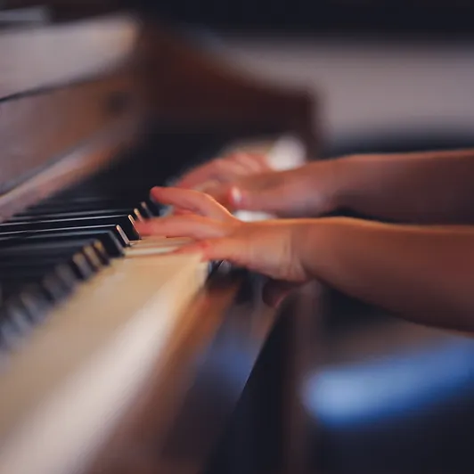 a background image of small, child-like hands playing at a piano
