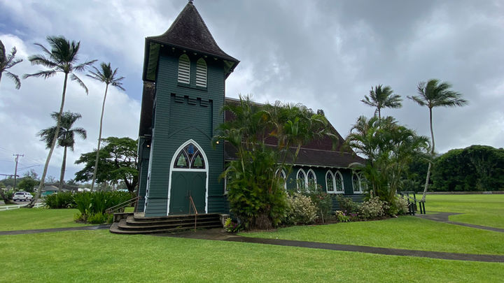 Famous historical Wai'oli Hui'ia Church, also known as the Green Church of Hanalei, in a grass field with palm trees