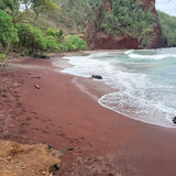 Low tide in Koki Beach with red sand and cinder cone cliffside in Hana, Maui.