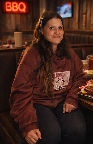 Woman seated indoors at a restaurant wearing a casual sweater