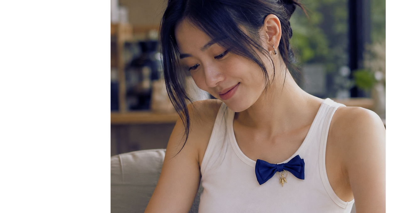 Woman in tank top with navy soft satin bow pin in front.