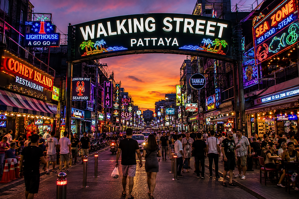 Walking Street Pattaya at sunset with illuminated signs and arriving visitors