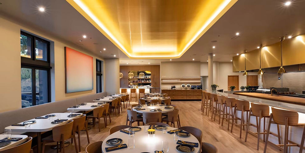 Modern upscale restaurant interior with ambient lighting, wooden furniture, and a well-stocked bar area