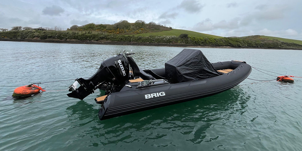 This used ribs for sale is a Black BRIG Eagle 6.7 Custom inflatable boat with Suzuki motor floats on calm water, tied to orange buoys. Green hills and cloudy sky in the background.
