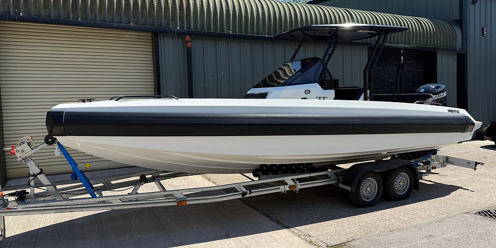 White IRON 707 boat with a black stripe on a trailer, parked outside a metal garage with a closed door. Sunny setting, engine visible. Used ribs for sale