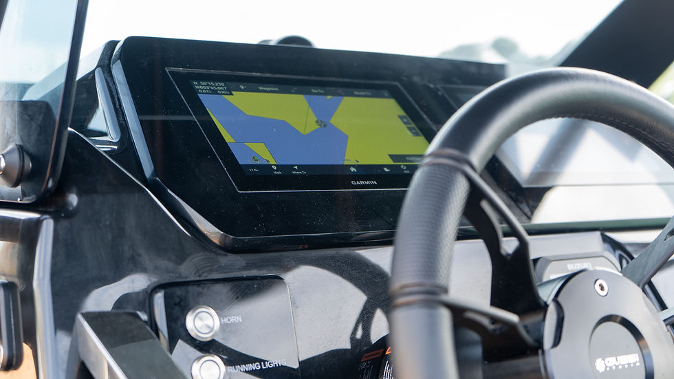 Brig Rigid inflatable boats dashboard with a Garmin GPS showing a yellow and blue map. Steering wheel in the foreground, buttons labeled Horn, Running Lights.