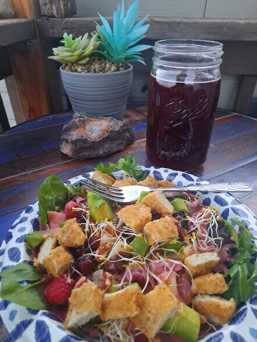 a healthy chicken salad served with a pomegranate drink on a patio table