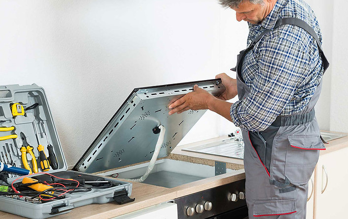 Repair specialist working on a stovetop's gas burner