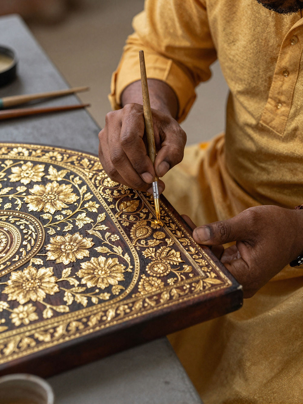 Artisan hand-painting intricate gold floral patterns