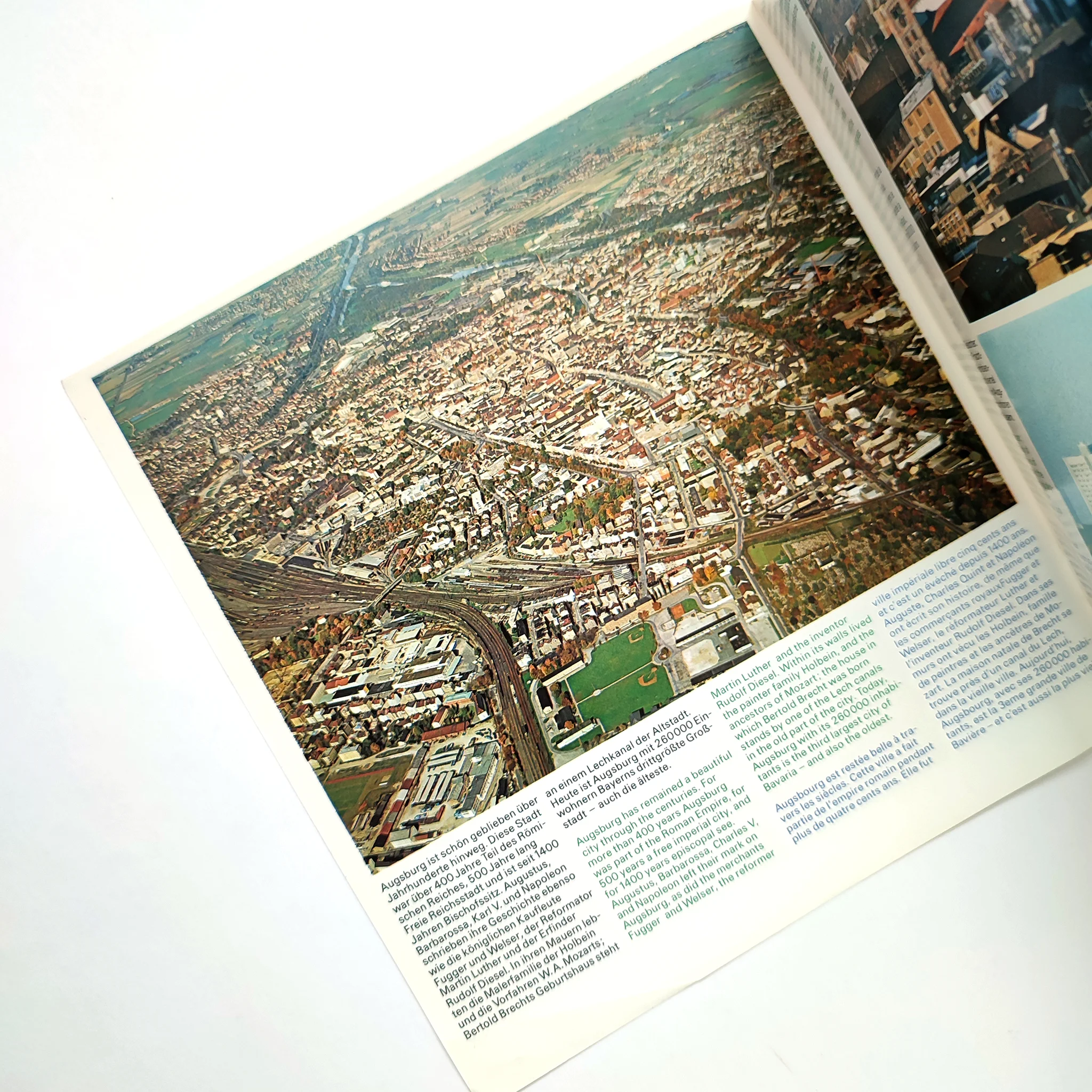 Aerial view of a city in a brochure, showing densely packed buildings and roads. Visible text at bottom. Mood is informative.