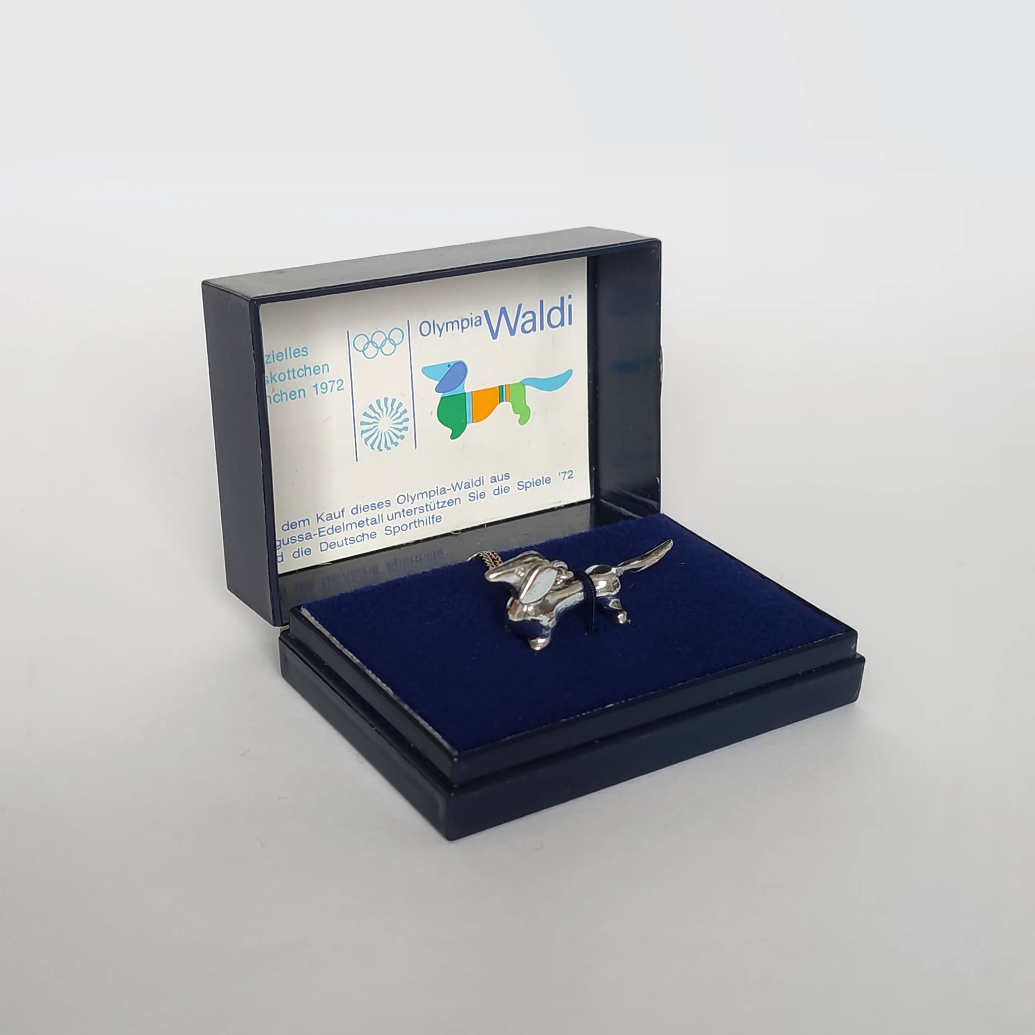 A silver pendant version of Olympia Waldi, the 1972 Olympic Games mascot, with necklace and box
