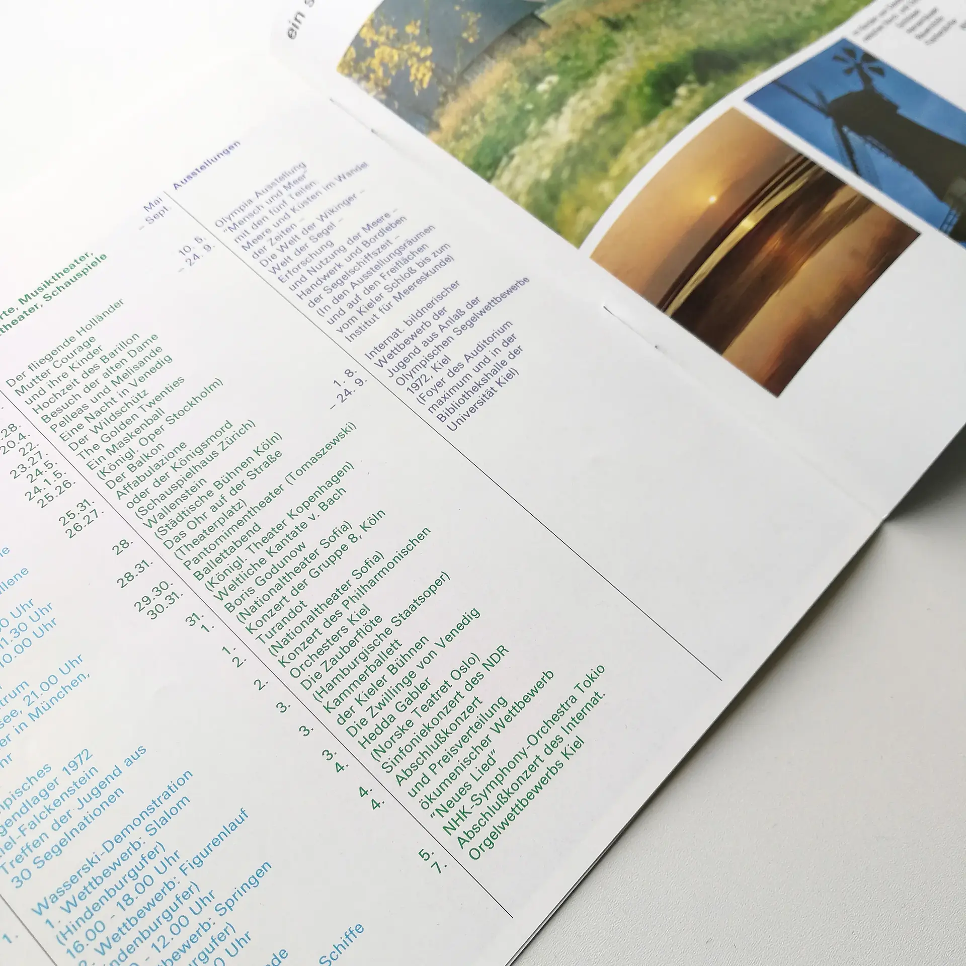 Open brochure on a white surface with a list of events in green and blue text. Photos of nature and a windmill are visible on the right.