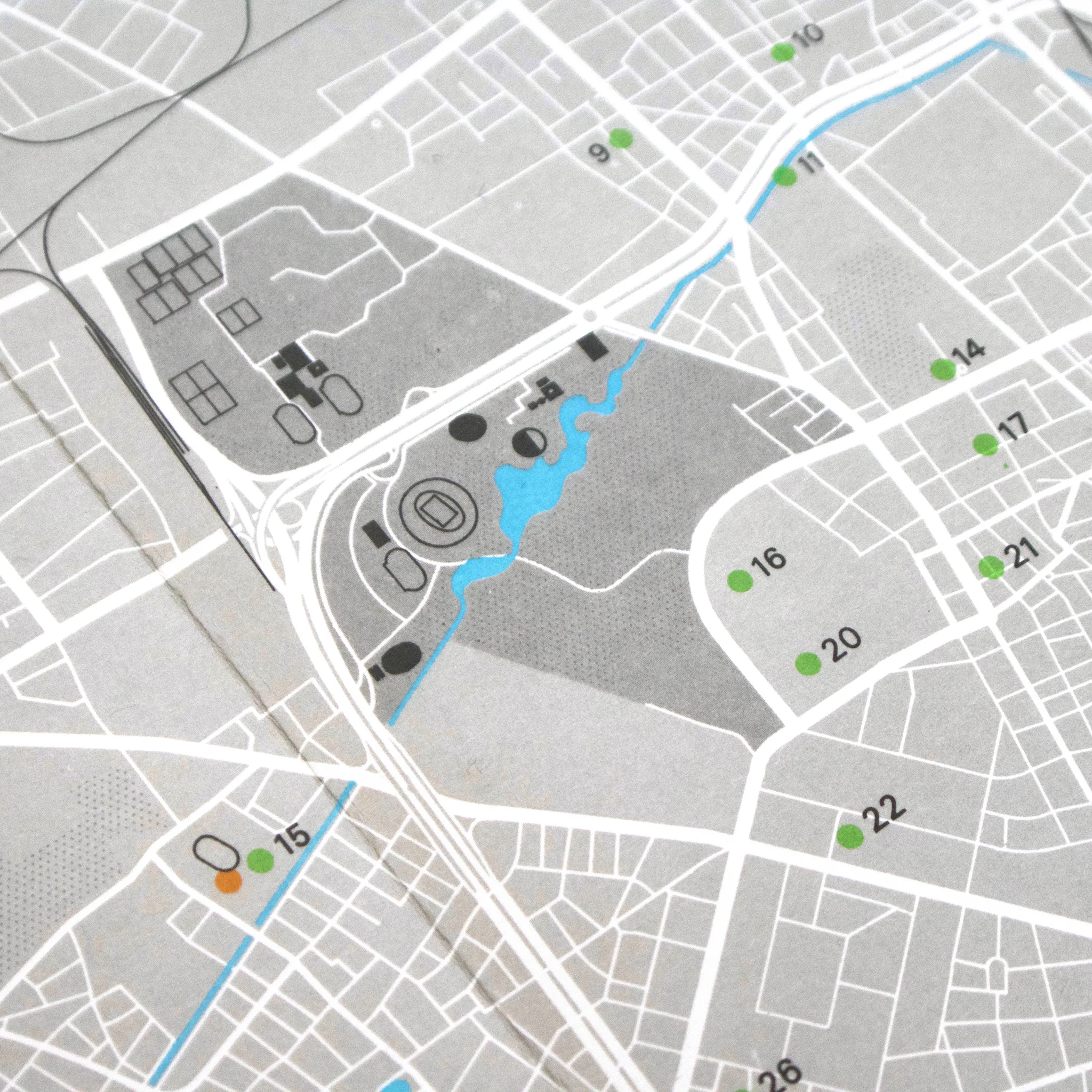 Map close-up with grey streets, marked points in green, blue river, and numbers like 9, 16, 22. A calm and structured layout.