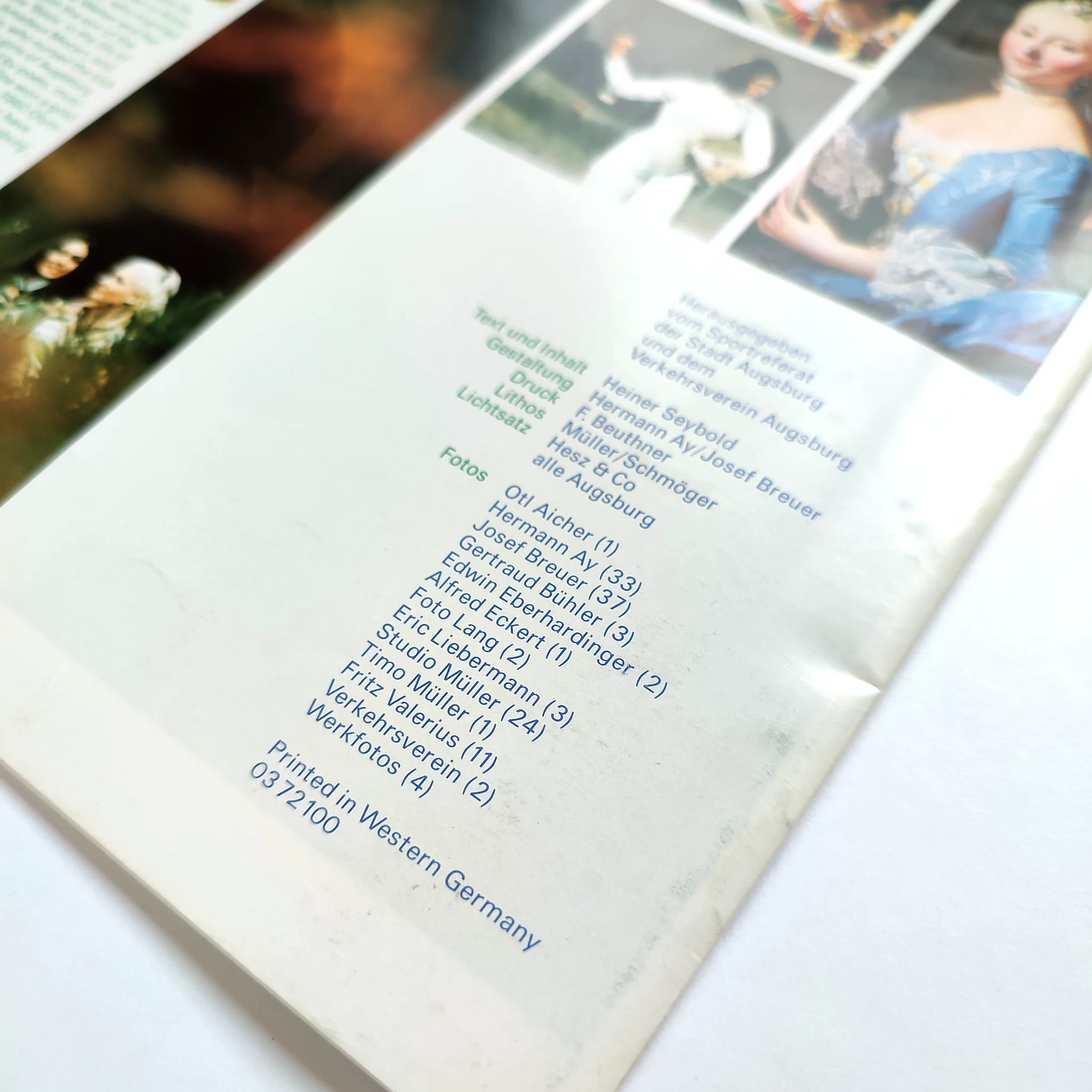 Brochure cover with text listing photographers and photos in blue and green. Background shows partial images of historical paintings. Printed in Western Germany.