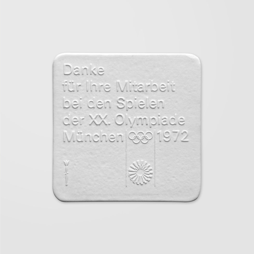 White ceramic plaque with relief text: Danke für Ihre Mitarbeit bei den Spielen der XX. Olympiade München 1972, featuring Olympic rings logo.