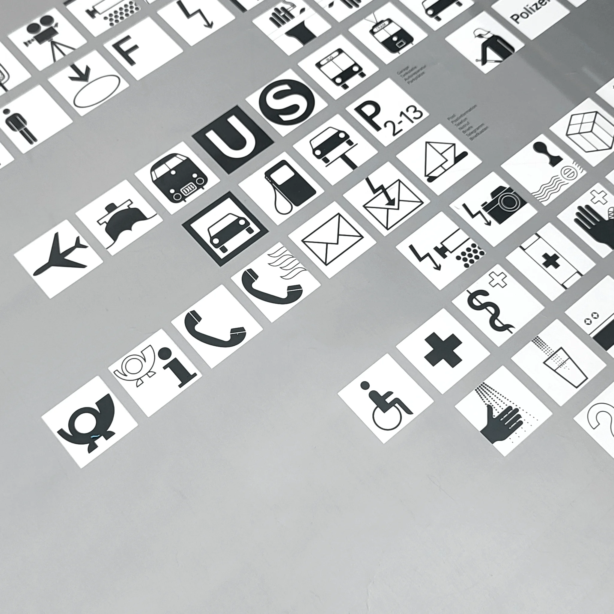 Black-and-white icon tiles with letters U S P 2-13, showing buses, mail, phones, medical and transport symbols on silver background