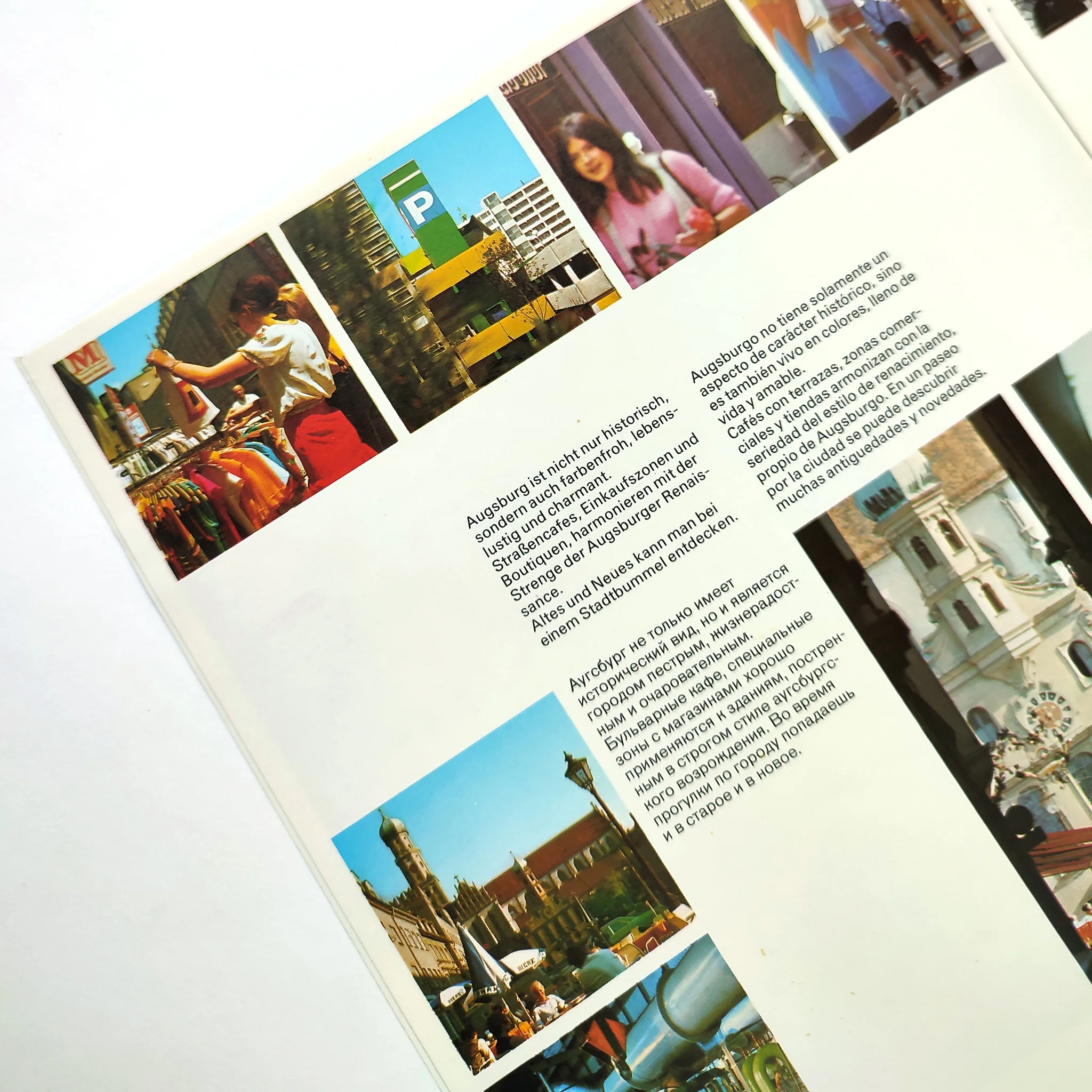 Brochure page with colourful images of people shopping, scenic buildings etc. Text in German, Spanish + Russian.